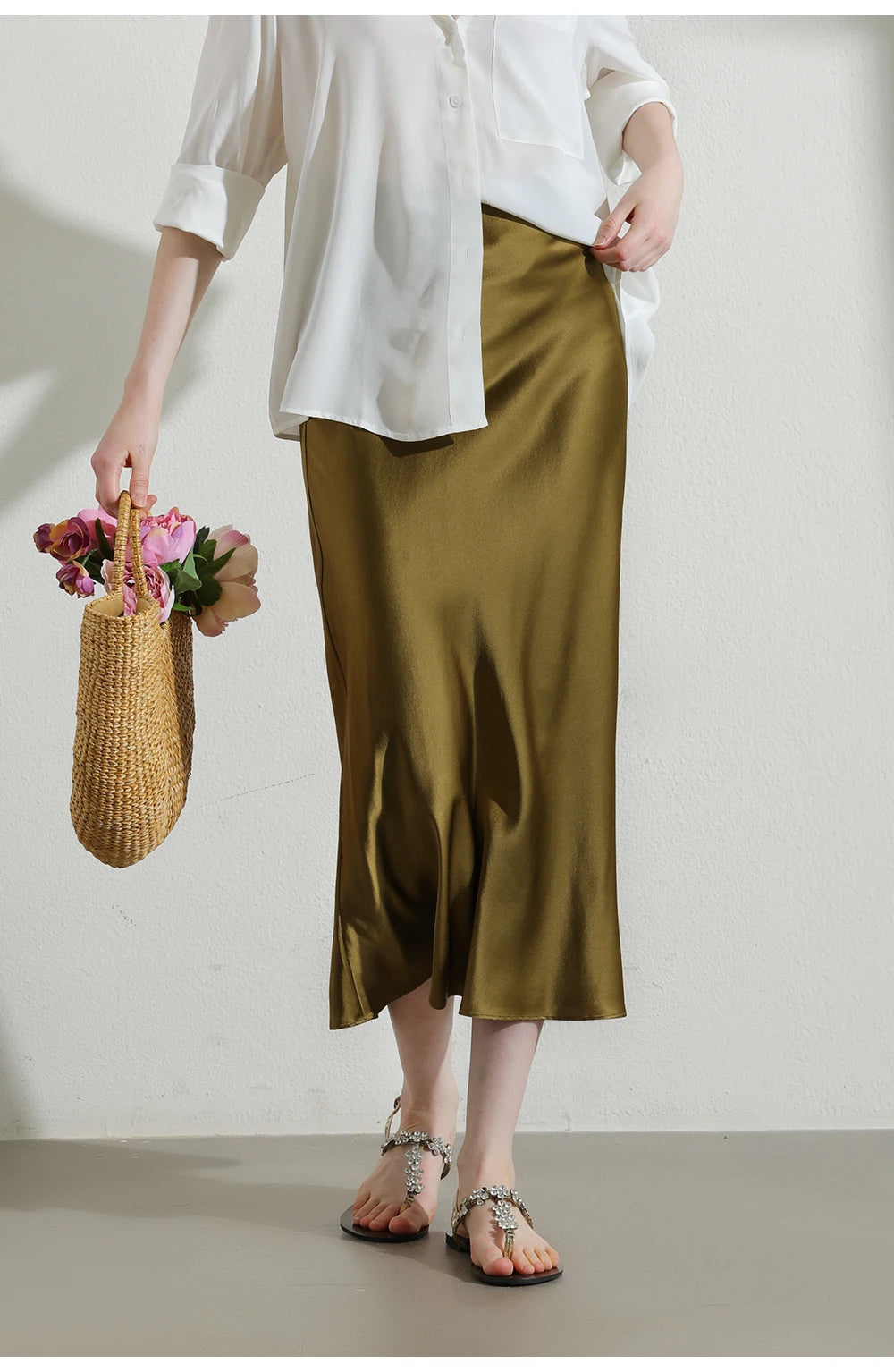 Model in Himalaya silk skirt holding soft-colored bag with visible flowers inside, suggesting composed styling. From Borcelleclothes.