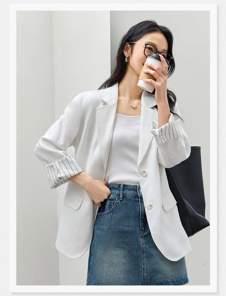 Close-up of a woman in the Alabaster Urban Blazer holding a cup of coffee near her face. From Borcelleclothes.
