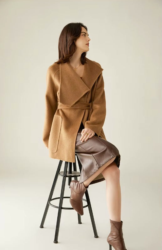 Collage of the Women's Asymmetrical Camel Hair Coat in Bourbon, featuring close-ups of a model adjusting the belt and touching the sleeve, highlighting the coat’s tailored details. From Borcelleclothes.