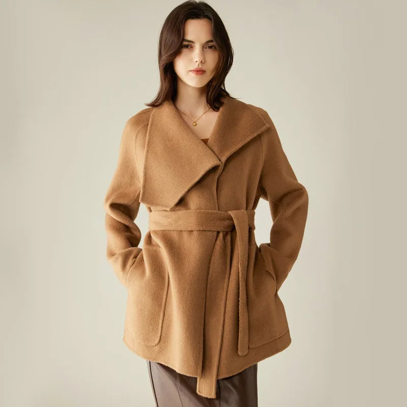 Women's Asymmetrical Camel Hair Coat in Bourbon—crafted from 100% double-sided camel hair for luxurious warmth and structure. Featuring asymmetrical lapels, raglan sleeves, a self-tie belt, and a sculpted silhouette, this mid-thigh coat blends artful elegance with modern refinement. From Borcelleclothes.