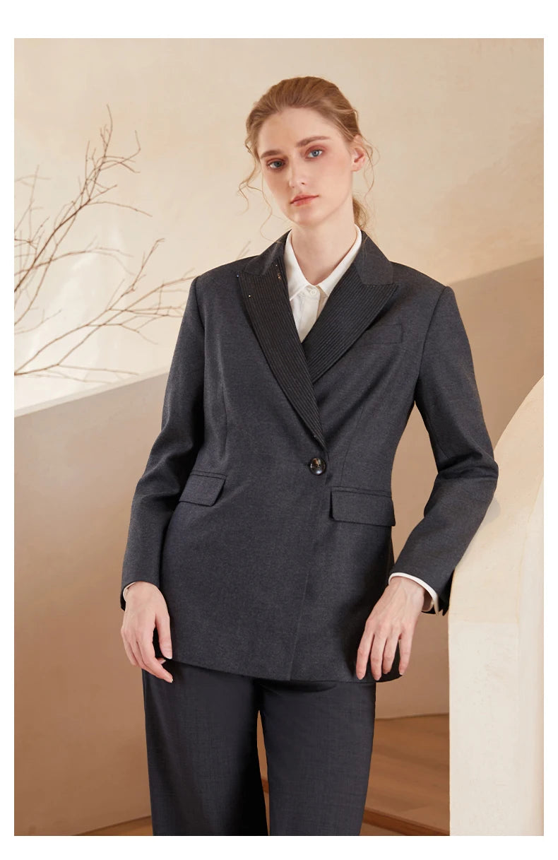 Women’s Australian wool blazer in Davy Grey with chain detail, model resting elbow on white staircase. From Borcelleclothes.
