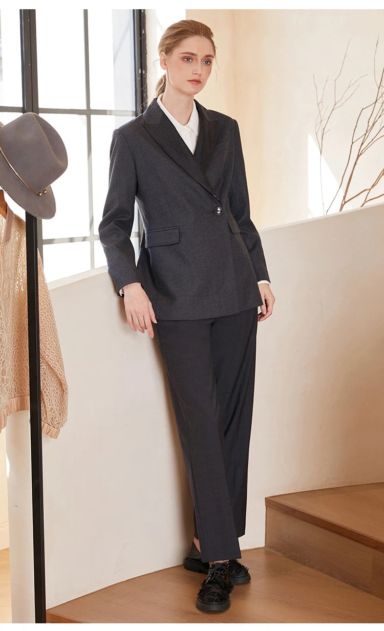 Women’s Australian wool blazer in Davy Grey with chain detail, model leaning against white staircase. From Borcelleclothes.