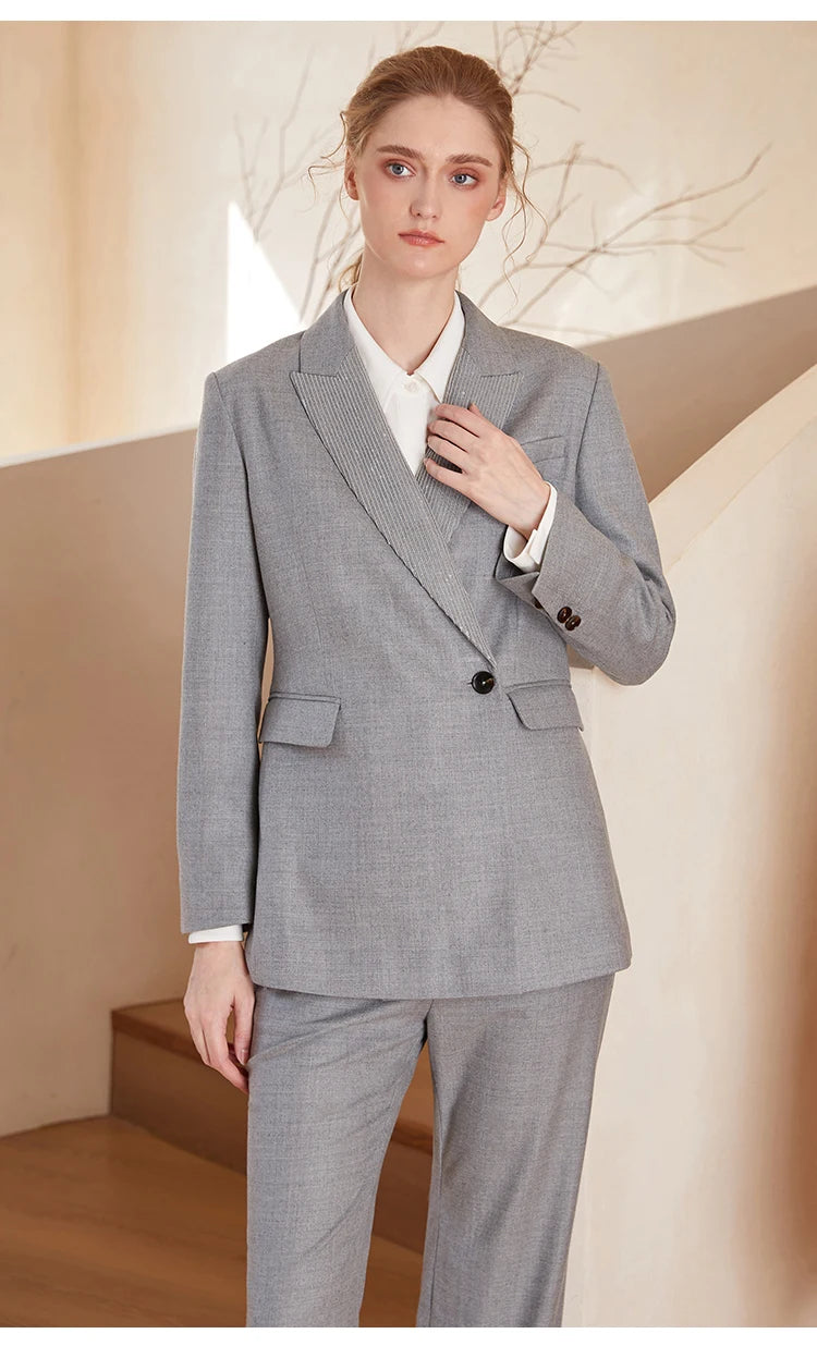 Women’s Australian wool blazer in Mountain Mist with chain detail, model touching lapel. From Borcelleclothes.