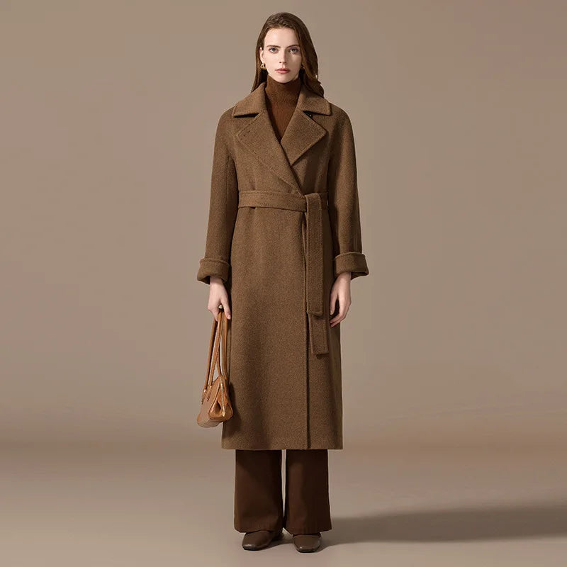 A model wearing the Women's Bactrian Camel Hair Coat in Irish Coffee, holding a bag, highlighting its elegant design and versatile styling. From Borcelleclothes.