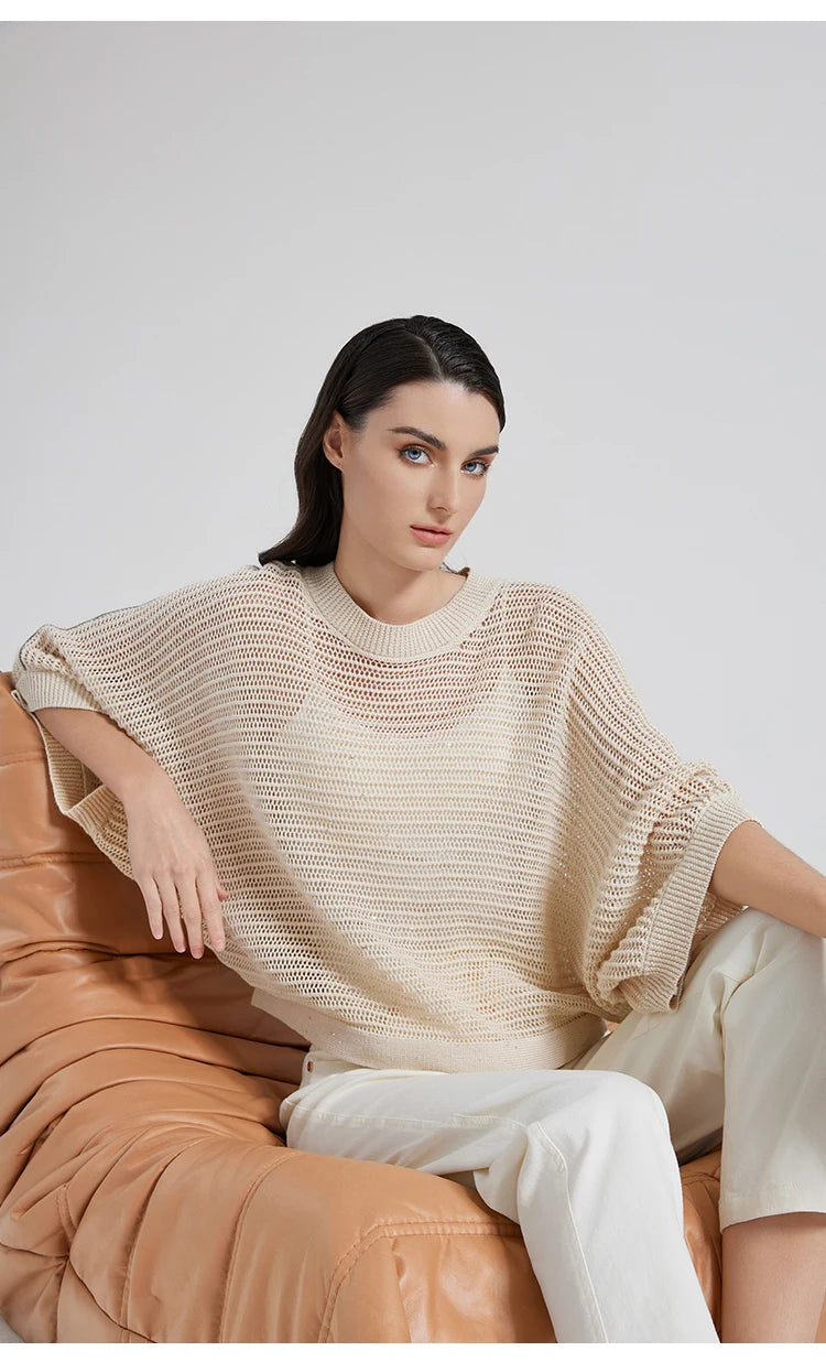 Woman in Spring Wood mesh top seated in an armchair, batwing sleeves resting in relaxed, sculptural folds. From Borcelleclothes.
