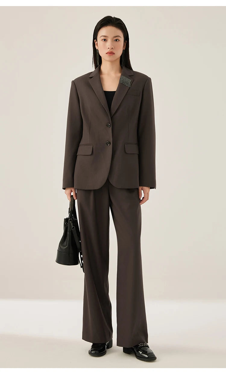 Woman wearing black chocolate blazer with rhinestone fringe detail, holding a bag – from Borcelleclothes.