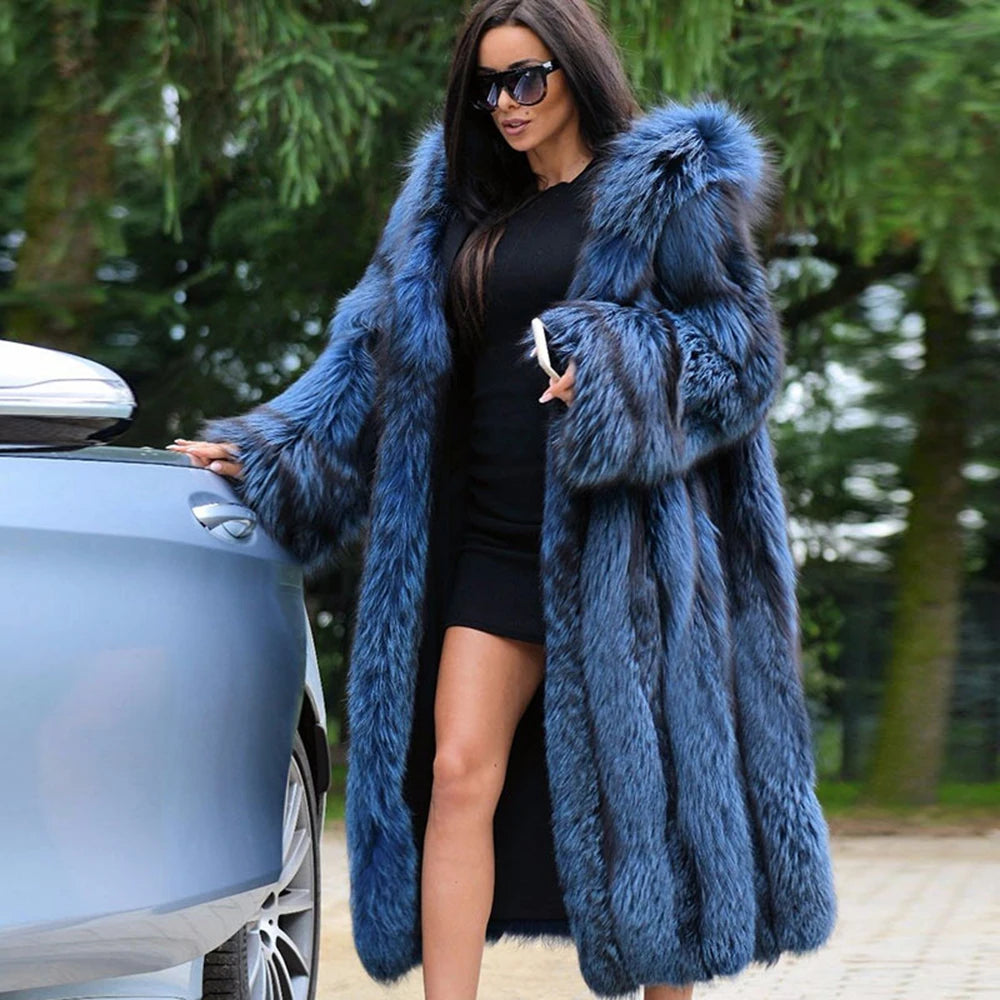 A woman draped in a sweeping Calypso silver fox fur coat, its deep blue tones shifting with movement. The expanded hood frames her presence, embodying fluidity and untamed allure. From Borcelleclothes.