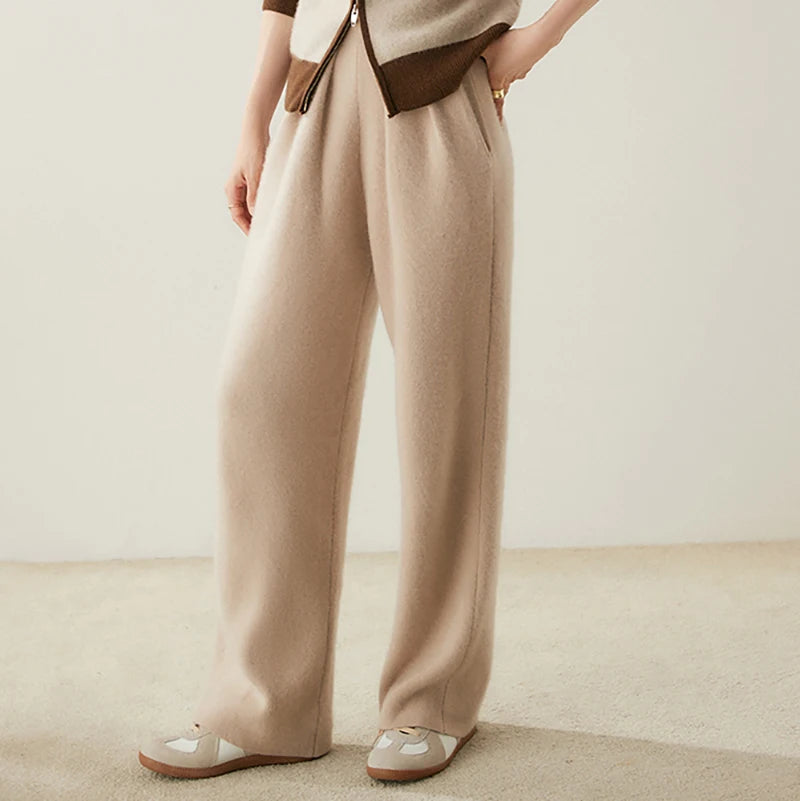 Model turned slightly to the side in Pale Taupe pleated cashmere trousers — From Borcelleclothes.