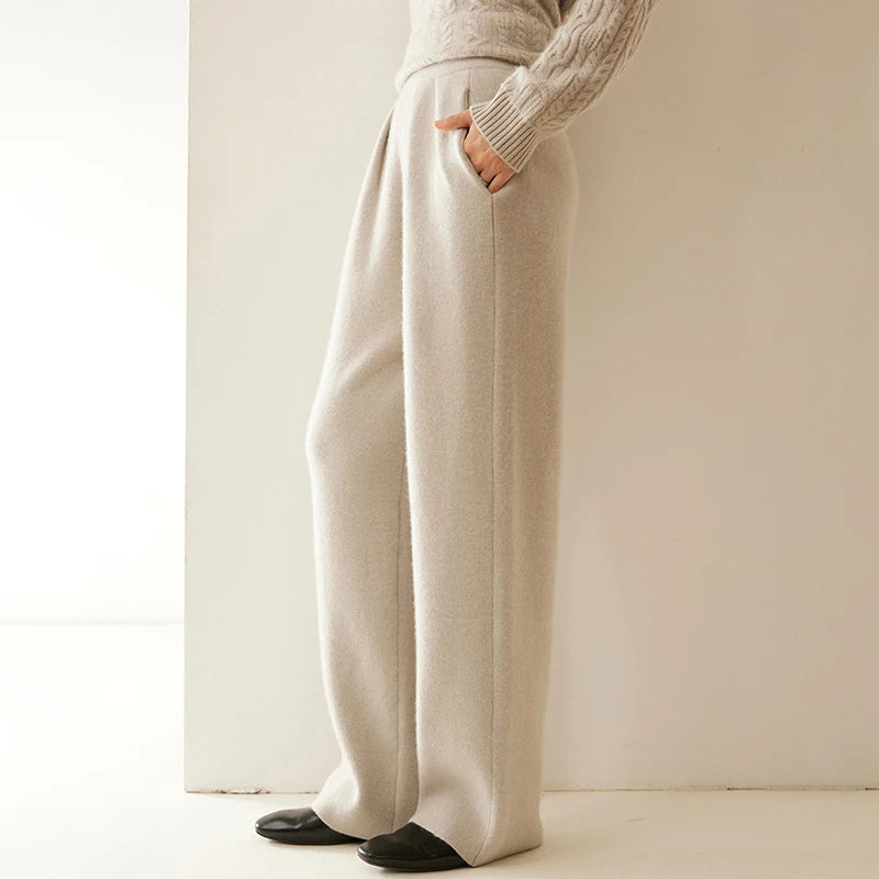 Model wearing Soft Amber pleated cashmere trousers, side view — From Borcelleclothes.