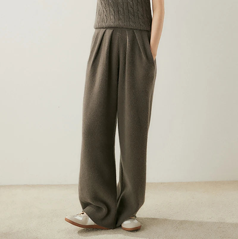 Model lifting toes while wearing Umber pleated cashmere trousers — From Borcelleclothes.
