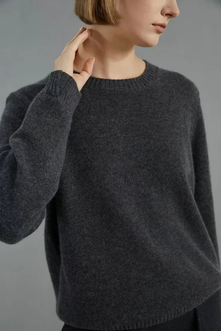 Women’s slim-fit cashmere sweater in Baltic Sea, with ribbed cuffs and subtle metal accents. Model touching her neck — From Borcelleclothes.