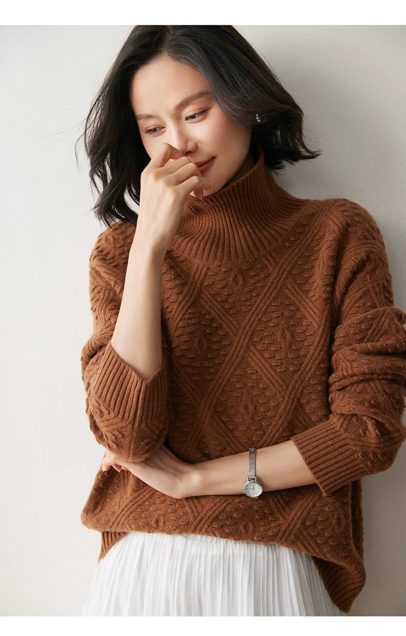 Model in Dark Russet cashmere sweater touching her nose and looking down, with interwoven diamond motif on sleeves — From Borcelleclothes.