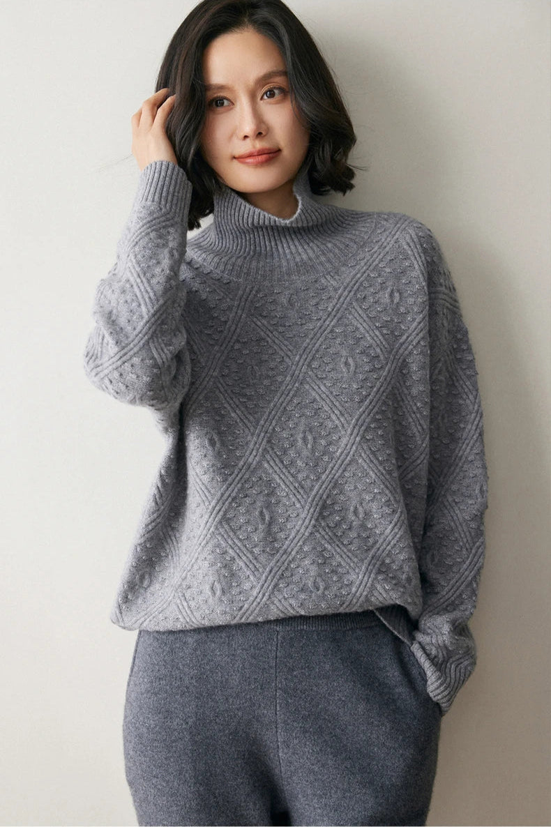Model adjusting her hair while wearing a French Grey cashmere sweater with a diamond motif and embossed bobble stitches — From Borcelleclothes.