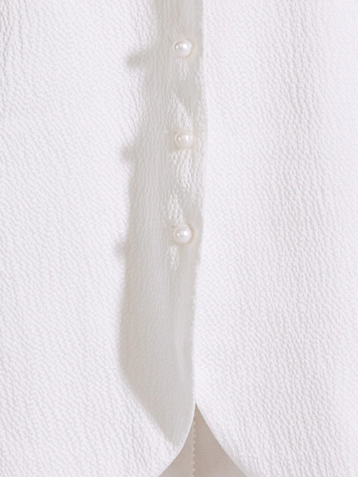 Close-up of the jacquard vest's front closure with pearl-like buttons. From Borcelleclothes.