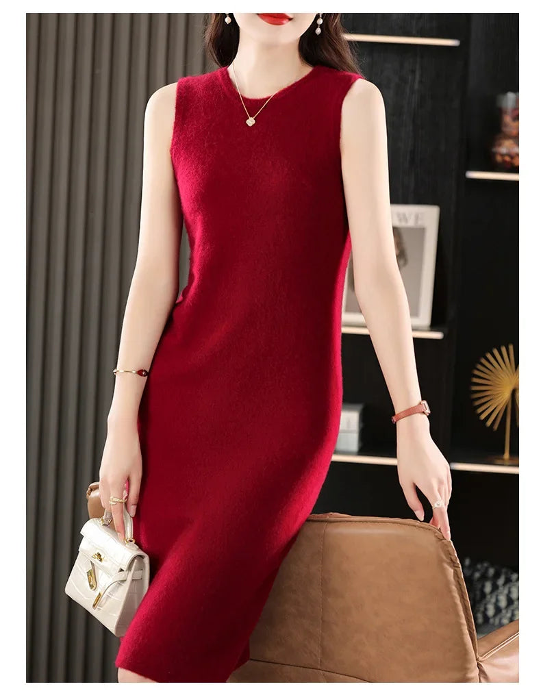 Woman in a Claret wool dress standing in front of an armchair. From Borcelleclothes.