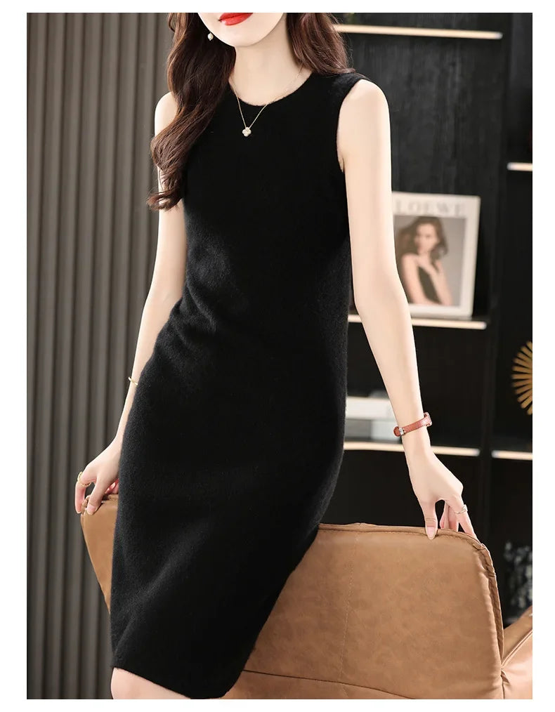 Woman in a Onyx wool dress standing in front of an armchair. From Borcelleclothes.