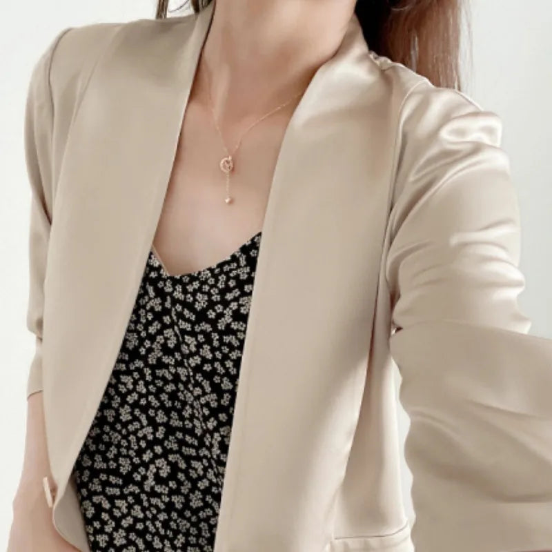 Woman wearing the collarless Mulberry silk jacket in Pearl Bush, upper part shown — revealing the open neckline and precise front construction. From Borcelleclothes.