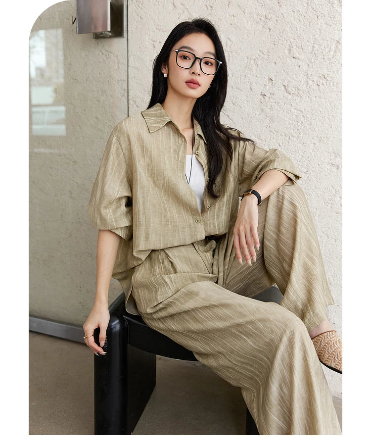 Woman in the Shadow set sitting casually on a chair, shirt partially unbuttoned. From Borcelleclothes.