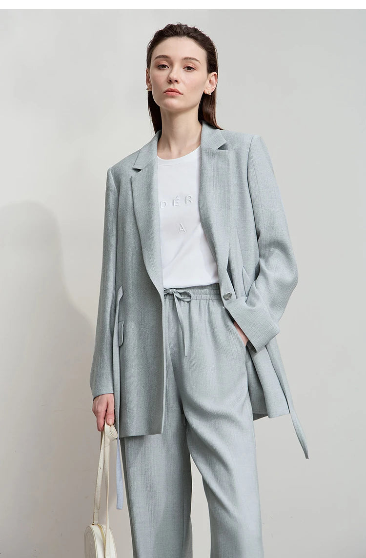 Woman with hand in blue pants pocket wearing Morning Blue crinkled viscose blazer – From Borcelleclothes.