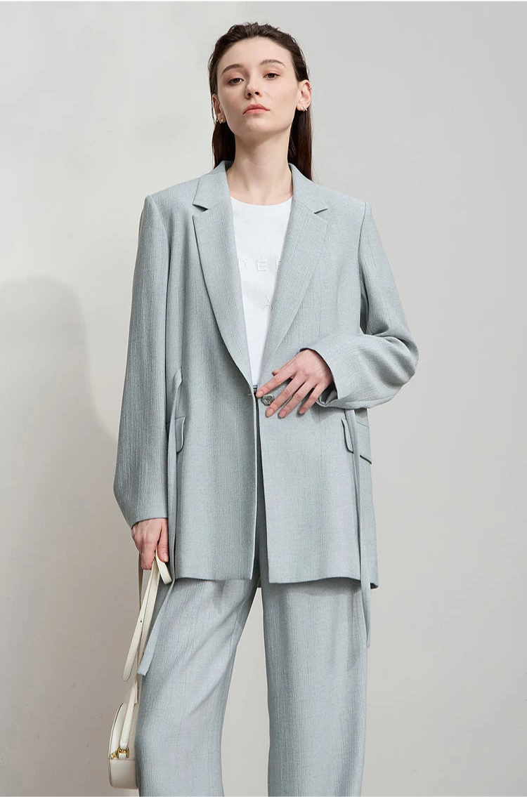 Woman touching front side while wearing unfastened Morning Blue crinkled viscose blazer – From Borcelleclothes.