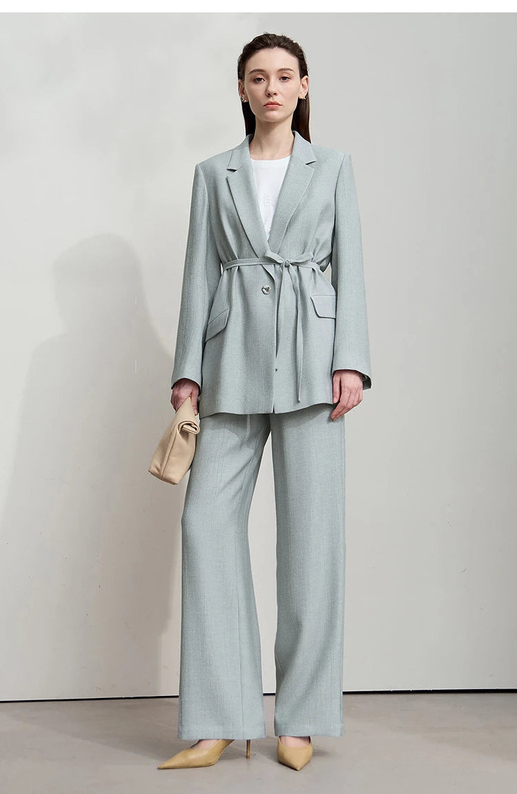 Women’s crinkled viscose blazer in Morning Blue, with deep textured folds, notch lapels, flap pockets, sculptural triangular button, and belt threaded through side openings. From Borcelleclothes.