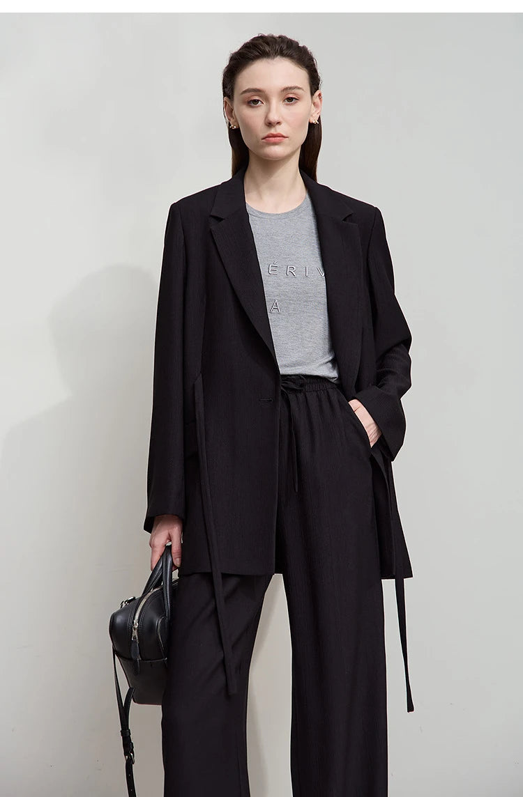Woman with hand in black pants pocket wearing Onyx crinkled viscose blazer – From Borcelleclothes.