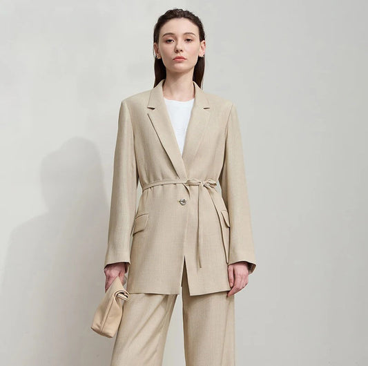 Women’s crinkled viscose blazer in Soft Amber, with deep textured folds, notch lapels, flap pockets, sculptural triangular button, and belt threaded through side openings. From Borcelleclothes.