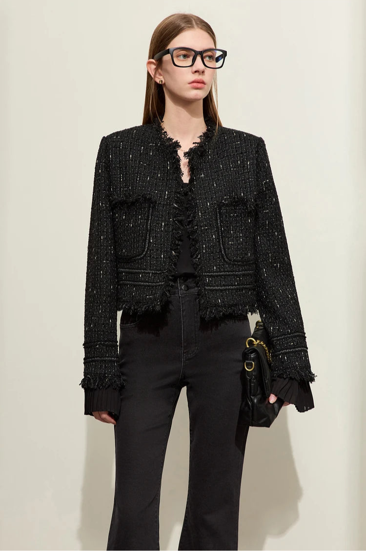 Model wearing Onyx cropped tweed jacket with sheer cuffs, holding black bag – From Borcelleclothes.