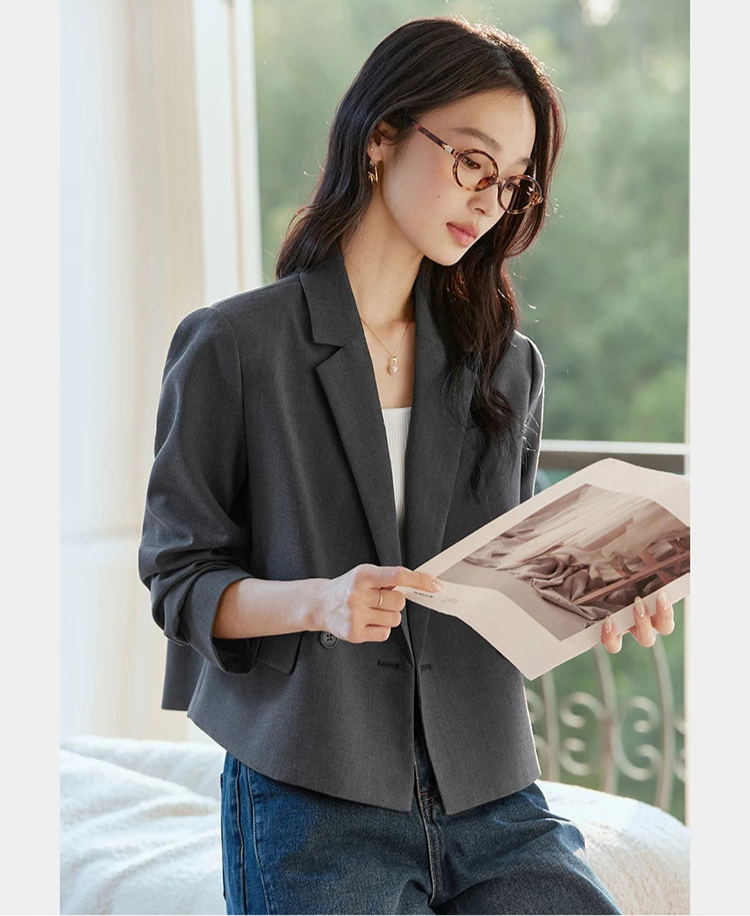 Model in Davy Grey double-breasted blazer with notch lapels, reading a journal. From Borcelleclothes.