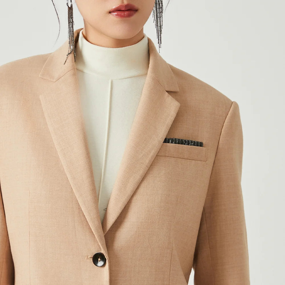 Close-up of woman wearing Desert Sand blazer, upper part with notch lapels visible. From Borcelleclothes.