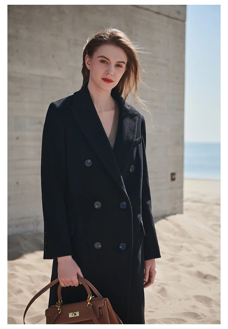 Woman wearing an Onyx double-breasted cashmere wool coat, holding a structured handbag. From Borcelleclothes.
