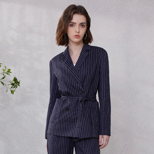 Woman in Mirage blue ramie blazer with wide stripes, hand placed behind back, showing double-breasted cut and waist belt – From Borcelleclothes.