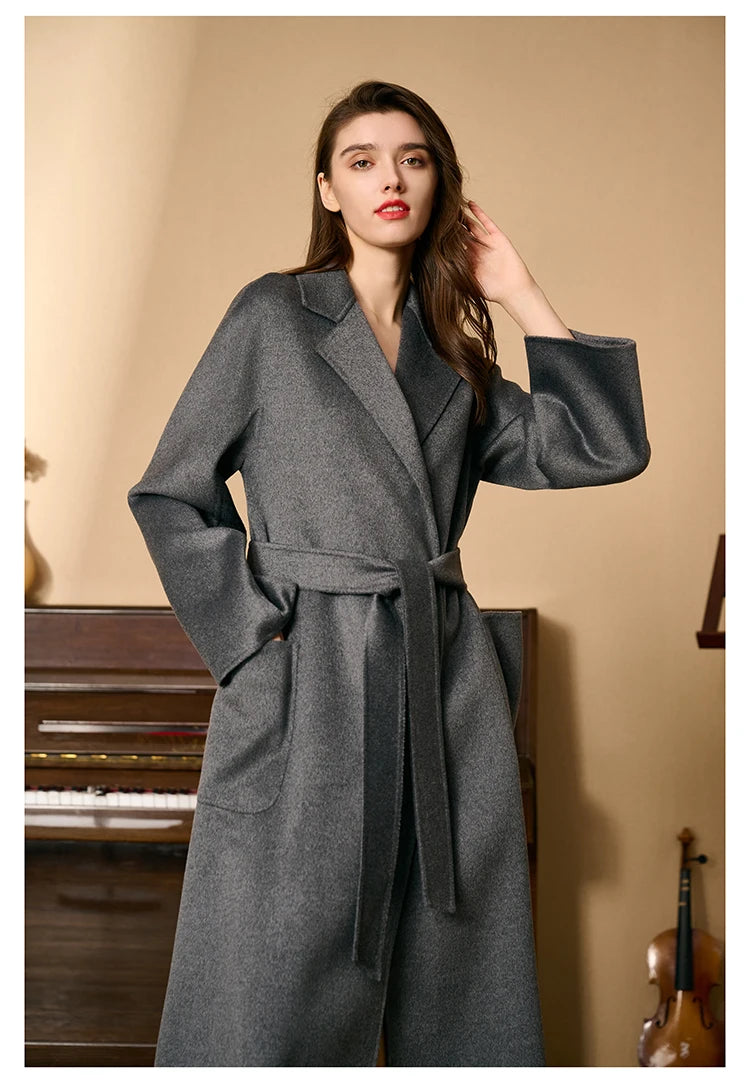 Model wearing a carbon grey double-sided cashmere wrap coat, touching her hair. From Borcelleclothes.