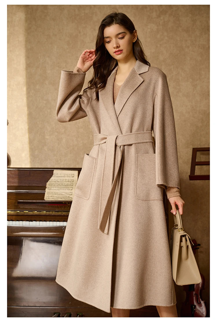 Model wearing a sandrift double-sided cashmere wrap coat, touching her hair. From Borcelleclothes.