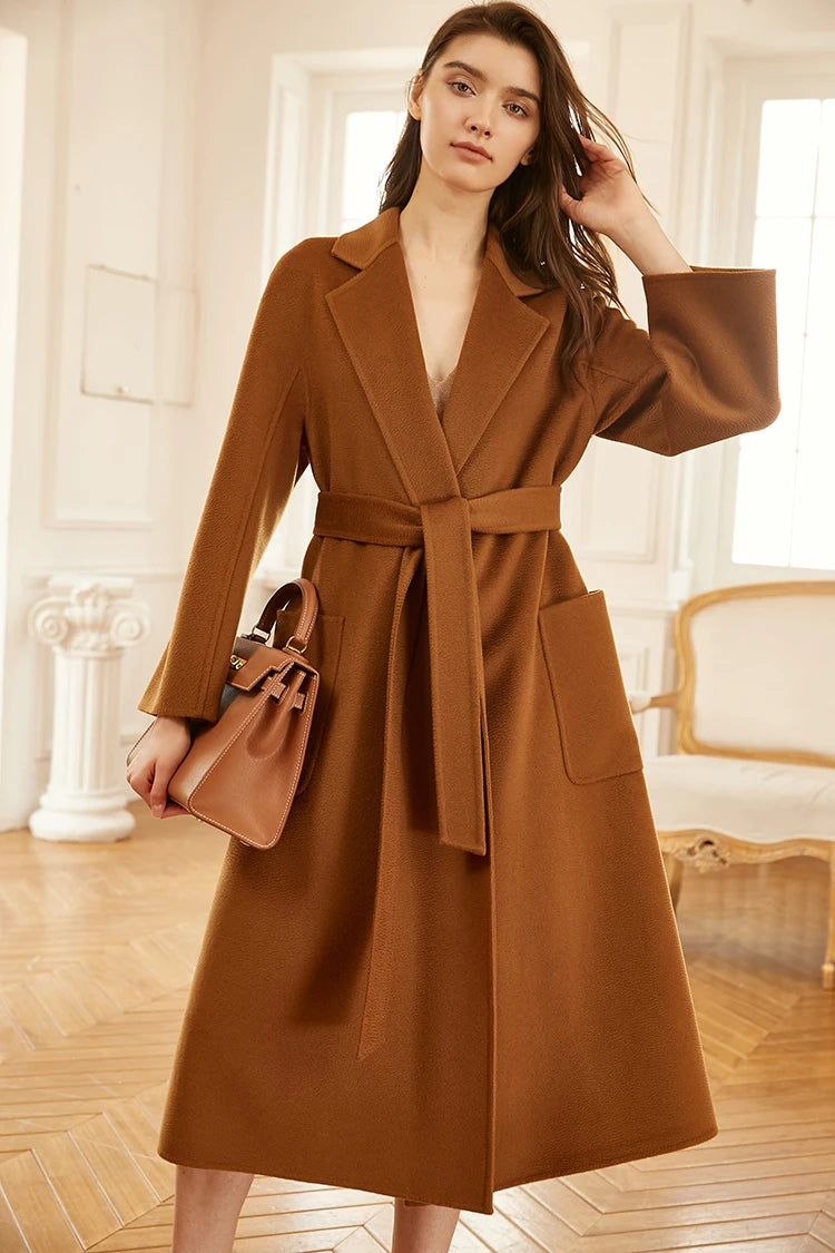 Model wearing a sienna double-sided cashmere wrap coat, adjusting her hair. From Borcelleclothes.