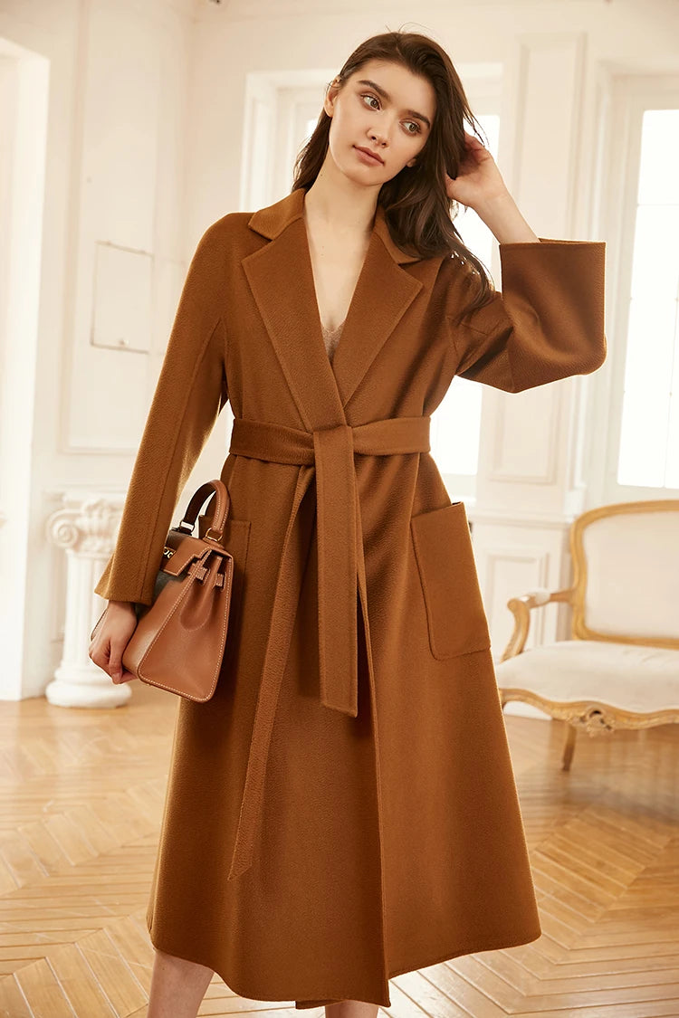 Model wearing a sienna double-sided cashmere wrap coat, touching her hair. From Borcelleclothes.