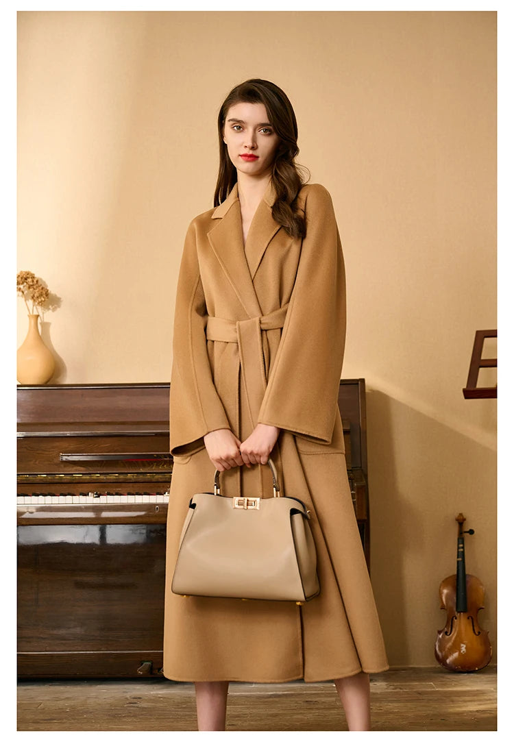 Model wearing a whiskey double-sided cashmere wrap coat, holding a bag with both hands. From Borcelleclothes.