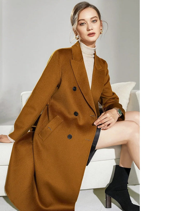 Model wearing the Women's Double-Sided Wool-Cashmere Coat in Bourbon, seated on a sofa, showcasing the coat's opulent fabric and elegant design. From Borcelleclothes.
