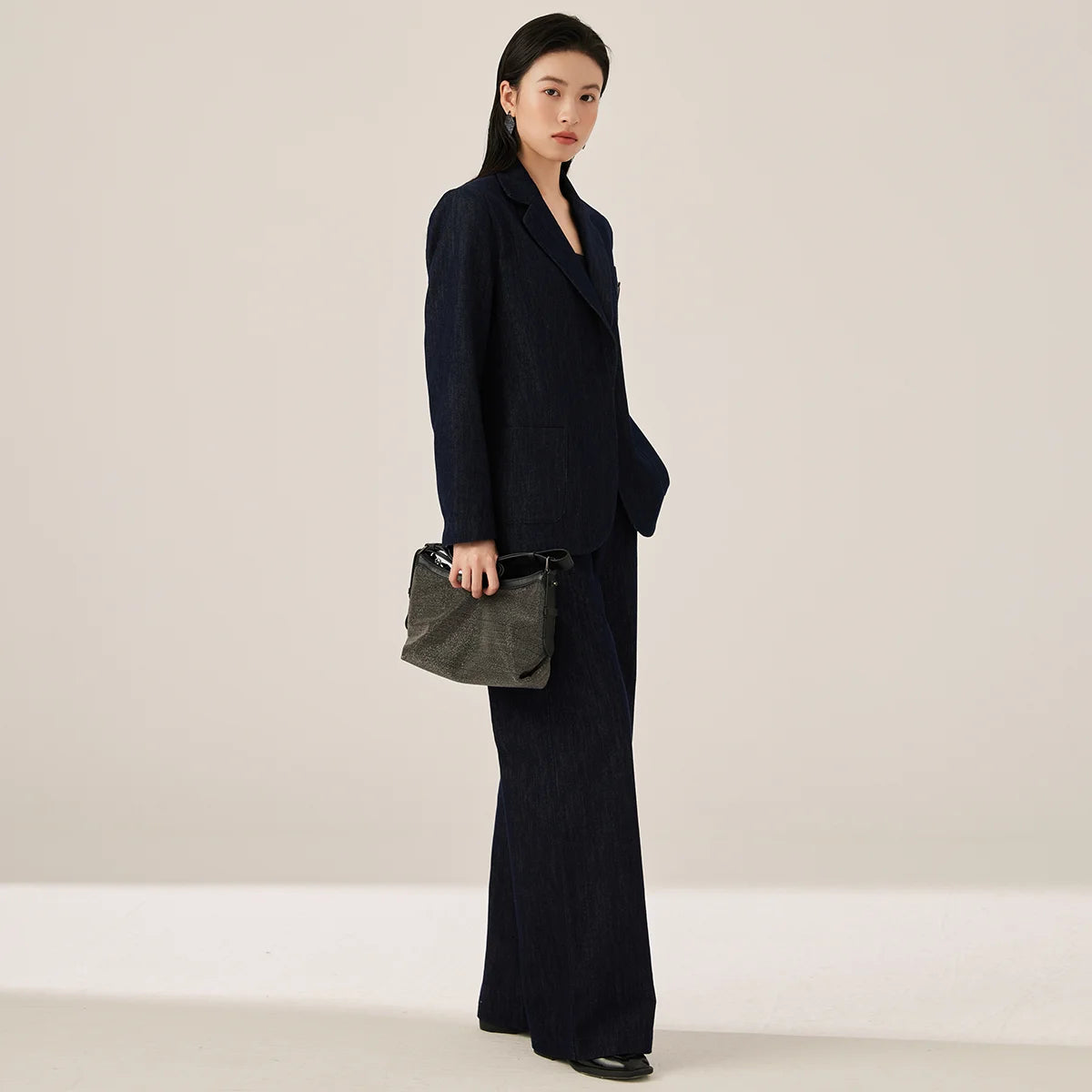 Woman wearing Ebony Clay denim blazer turned slightly to the side, showing classic notch lapels and relaxed silhouette – From Borcelleclothes.