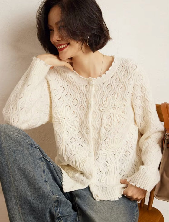 A model smiling and gazing to the side, dressed in the women's Embossed Lace Cashmere Cardigan in Pearl Bush, showcasing its timeless elegance and intricate lace design, Borcelleclothes.