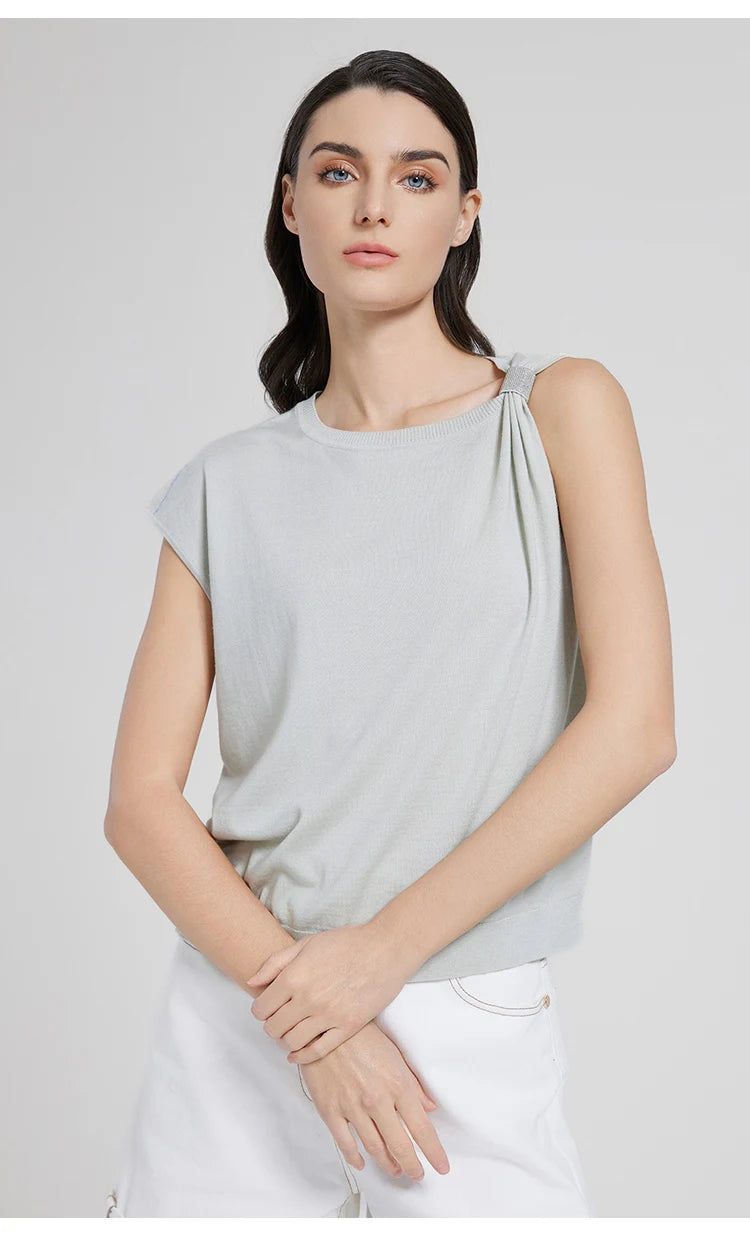 Model wearing the Geyser top gently holding her wrist, with a focus on the shimmer and neckline curve. From Borcelleclothes.