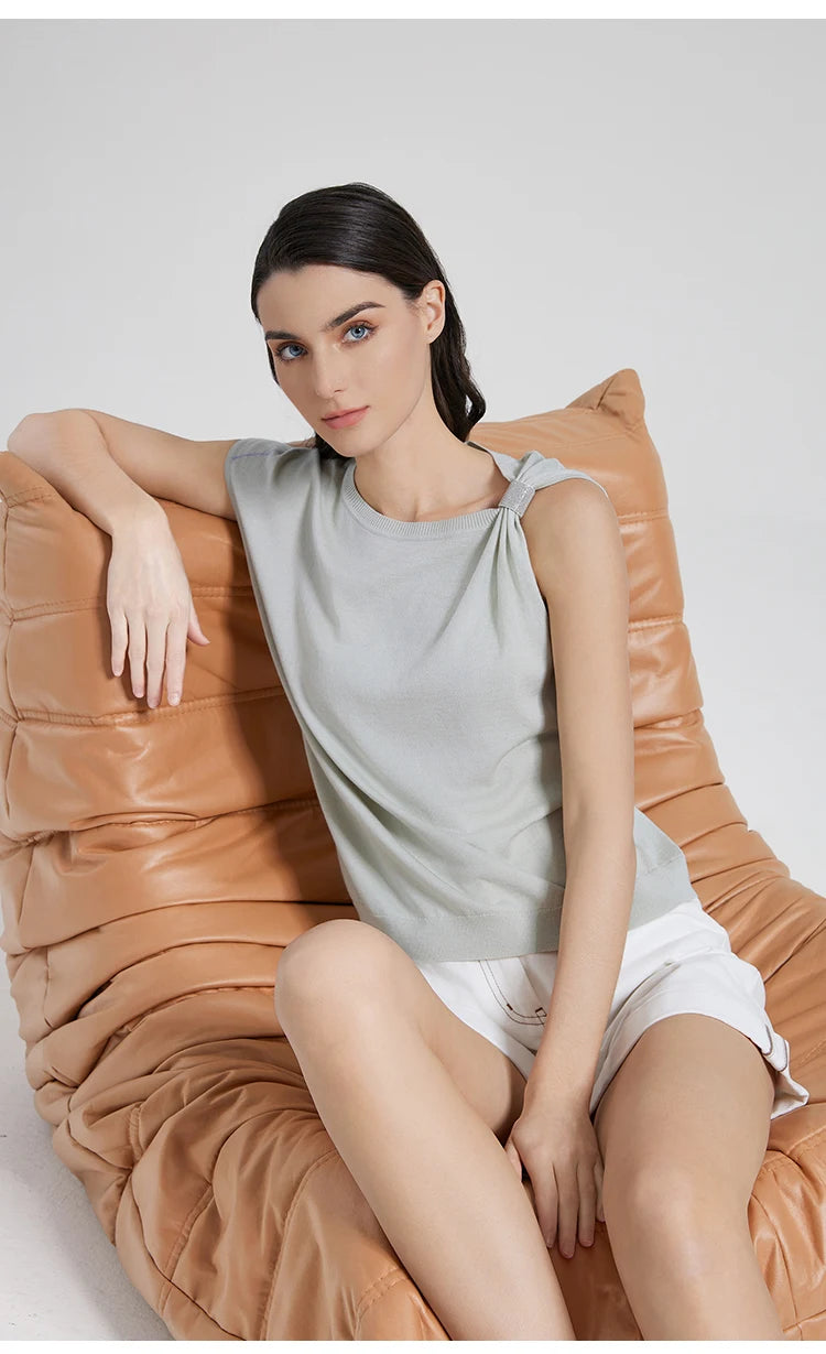 Model in Geyser top seated in an armchair, capturing the soft elegance of the fabric and asymmetry. From Borcelleclothes.