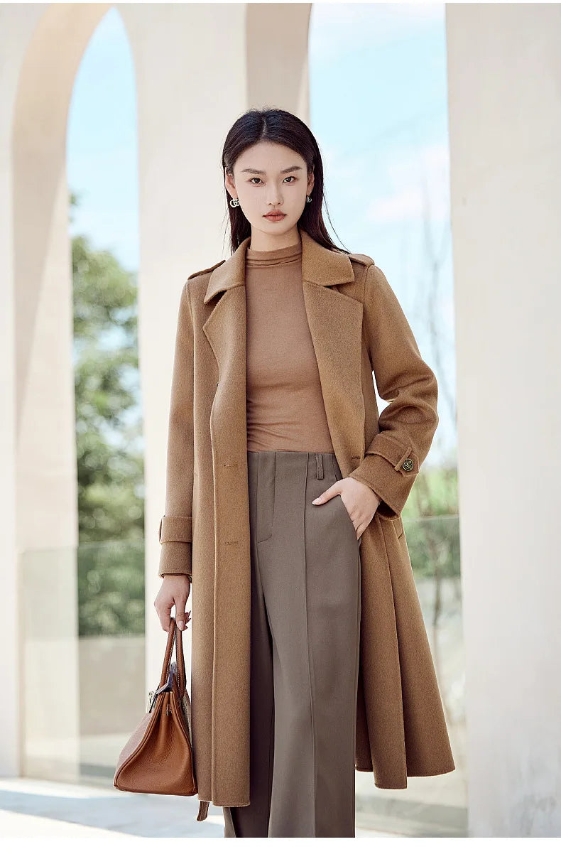 A model wearing the Women's Grade A Cashmere Coat in French Beige, placing a hand in a pant pocket, highlighting its relaxed yet polished styling. From Borcelleclothes.