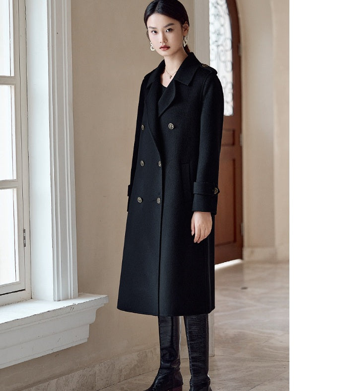 A model wearing the Women's Grade A Cashmere Coat in Onyx, turned slightly to the side, emphasizing its elegant drape and tailored fit. From Borcelleclothes.