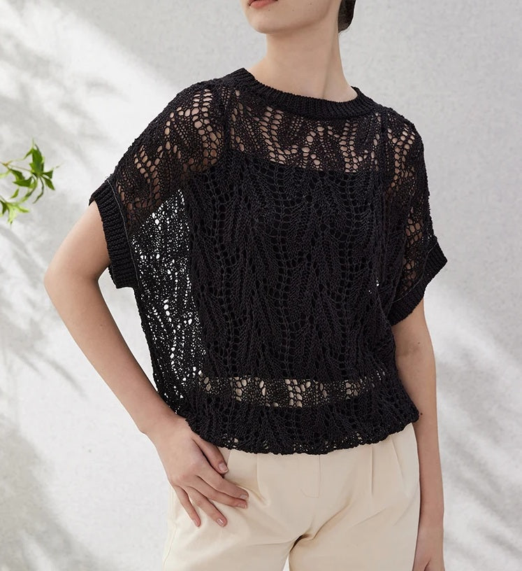 Woman in Onyx hollow knit top with one hand on hip, showcasing the contrast between dense rib trim and airy leafwork. From Borcelleclothes.