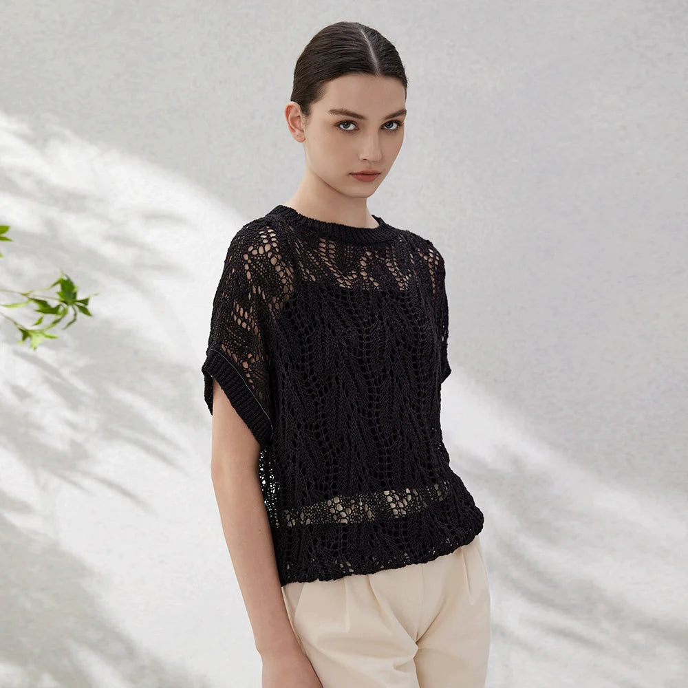 Woman wearing a black linen lace top with hollow leaf-pattern knit, turned slightly to the side to reveal the open structure. From Borcelleclothes.