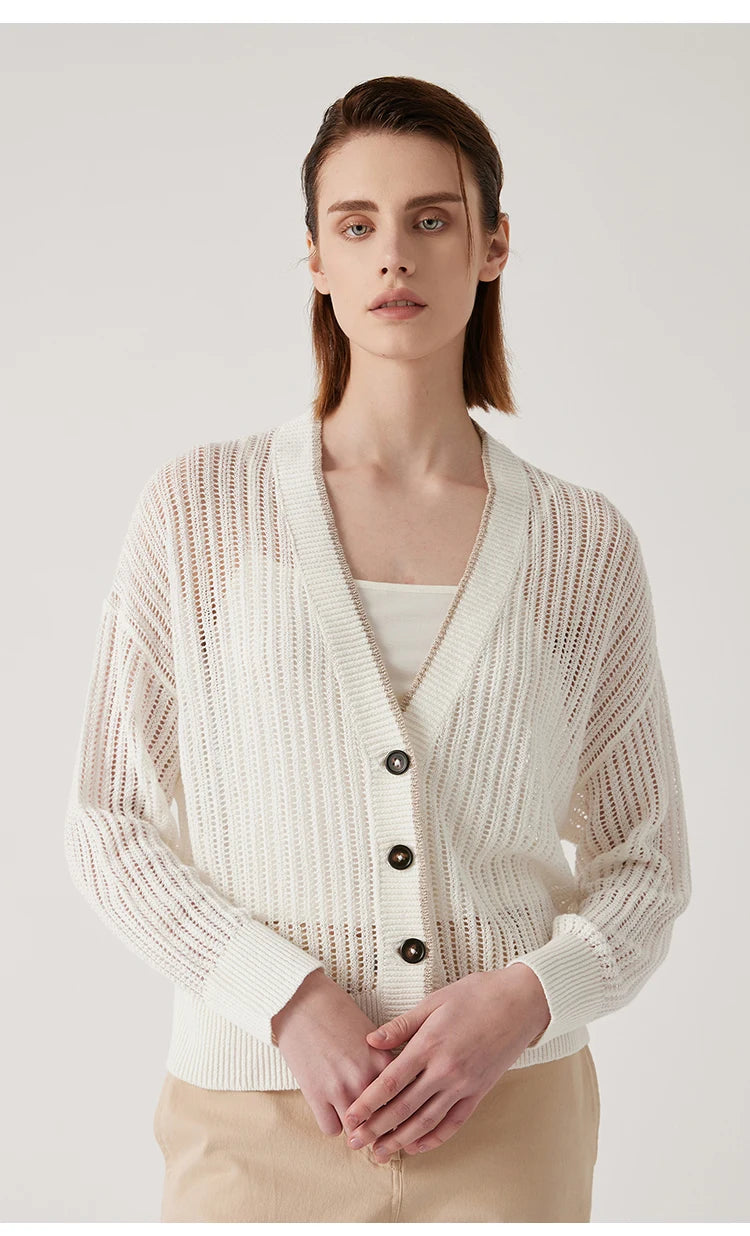 Woman in Wild Sand linen cardigan, hands softly meeting in front, accenting button placket and open knit structure. From Borcelleclothes.
