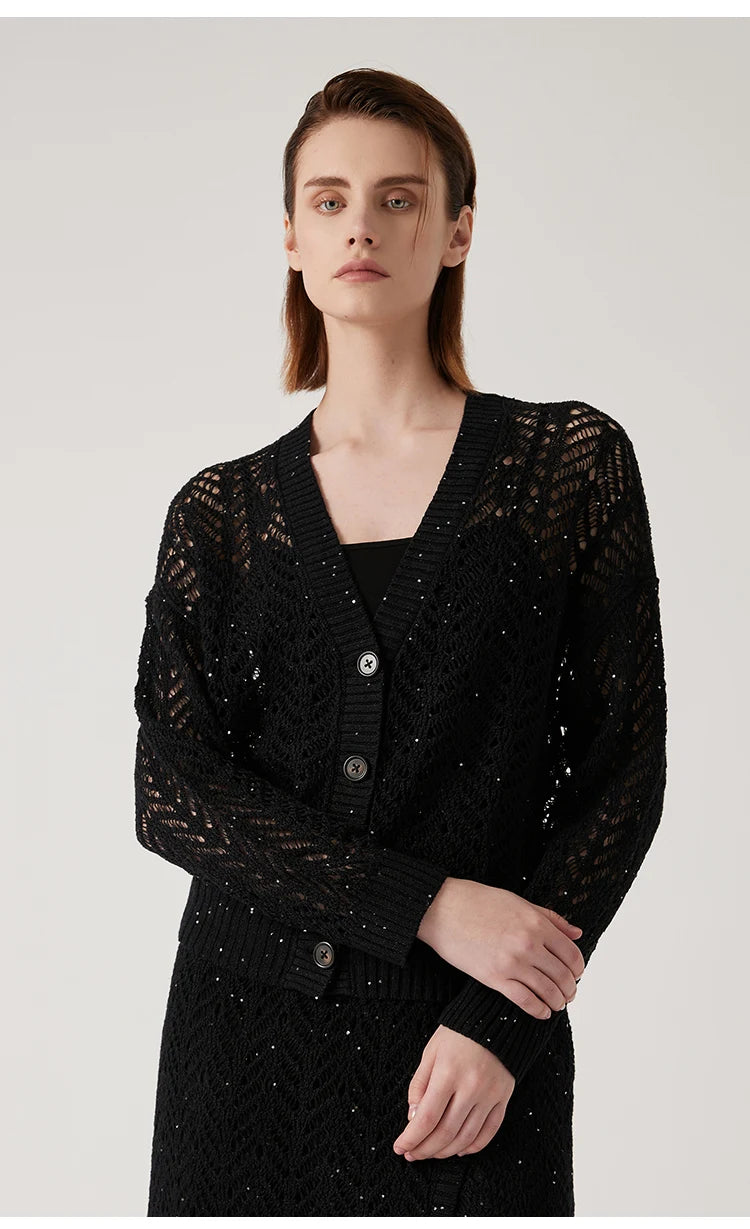 Model gently touching the sleeve of the Onyx cardigan, drawing attention to the intricate lace pattern. From Borcelleclothes.