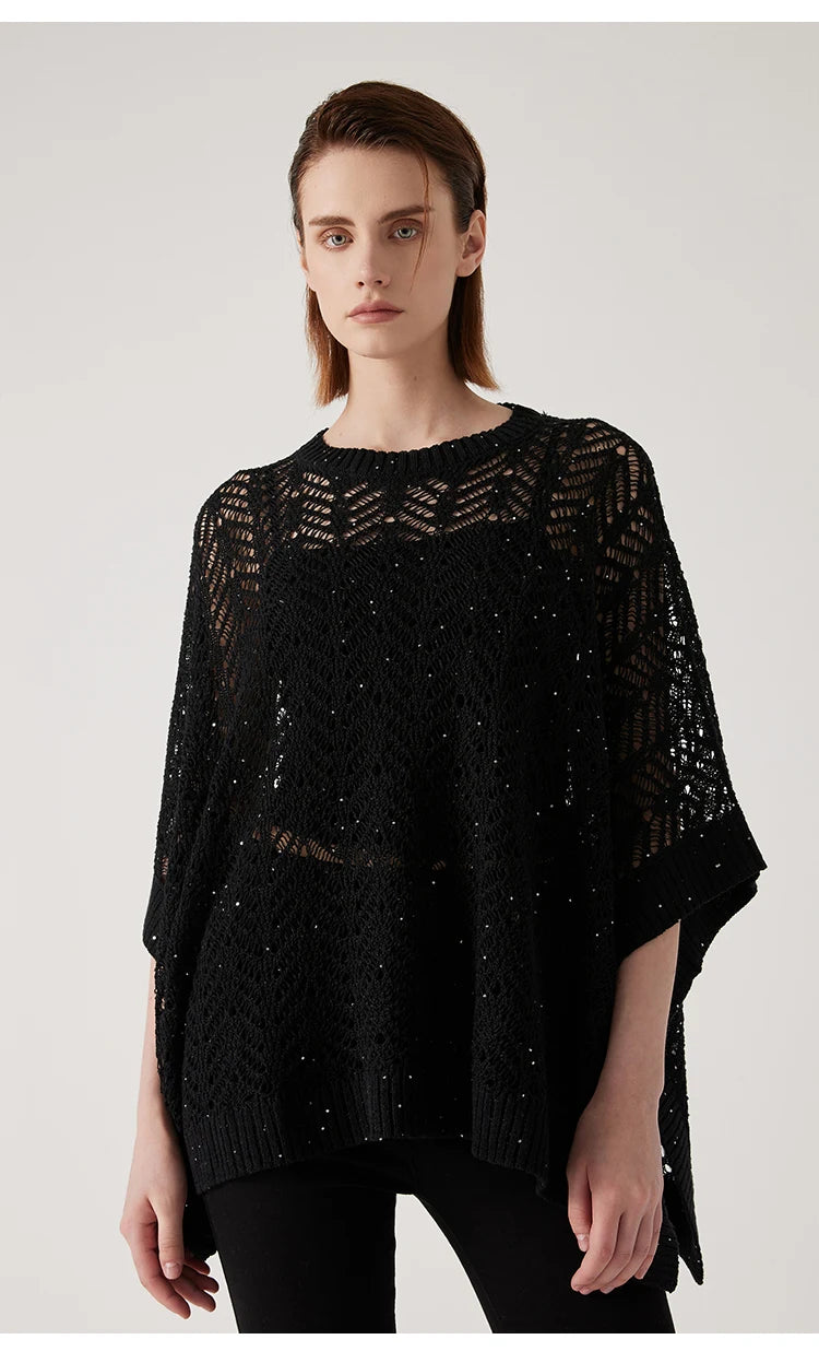 Woman in Onyx lace poncho standing with arms straight, showcasing underarm tacking and sheer, branch-like knit pattern. From Borcelleclothes.