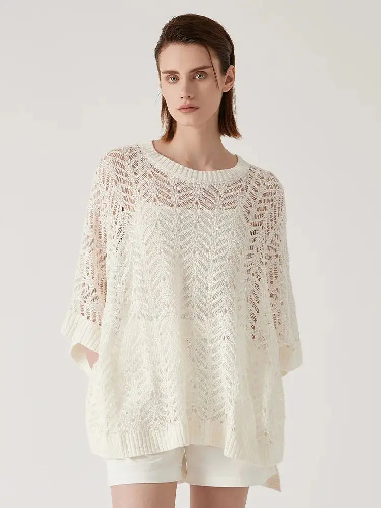 Woman in Pearl Bush lace poncho with hands behind her back, showing delicate underarm seam and flowing rectangular form. From Borcelleclothes.